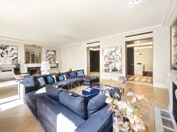 Salon spacieux d'un appartement rénové à Paris, avec canapé bleu et décoration élégante.