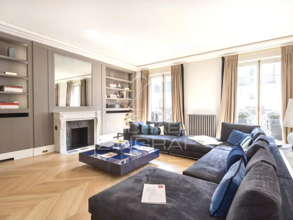 Salon d'un appartement refait à neuf avec un canapé bleu et une cheminée, situé à Paris 8ème.
