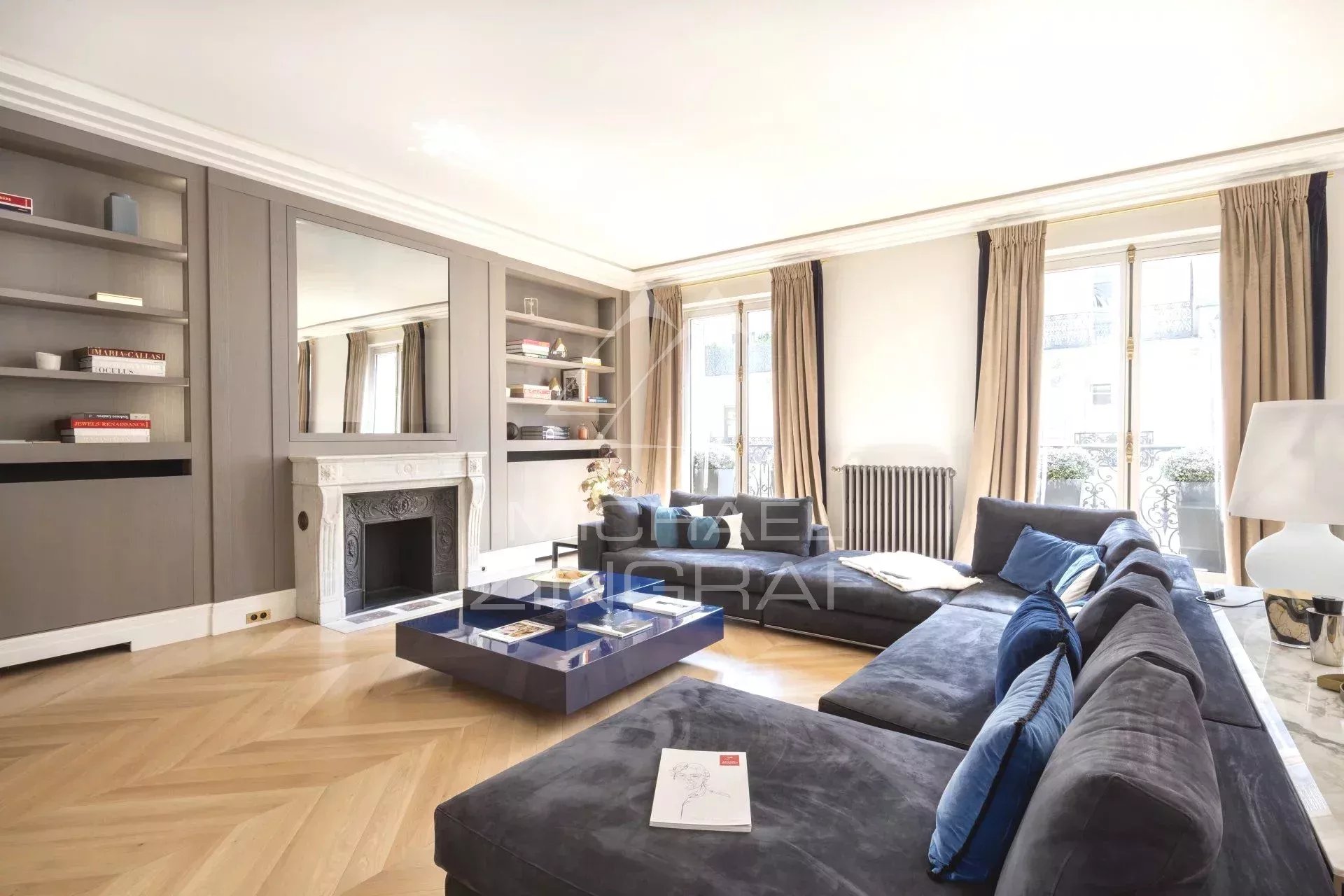 Salon d’appartement à Paris 8ème Salon d'un appartement refait à neuf avec un canapé bleu et une cheminée, situé à Paris 8ème.