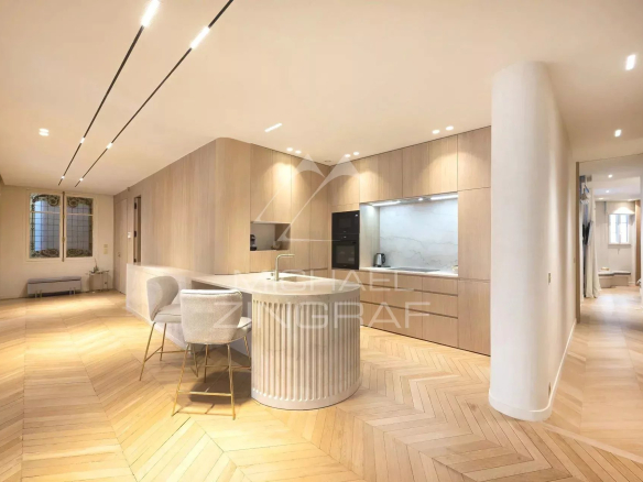 Interior of a modern apartment with open kitchen and wooden parquet flooring, located in Paris.