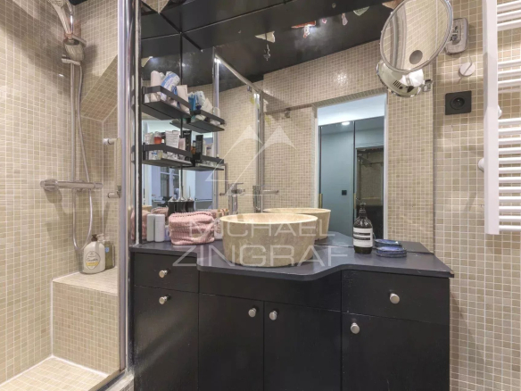 Salle de bain moderne avec douche, lavabo et miroir, dans un appartement rénové à Paris.