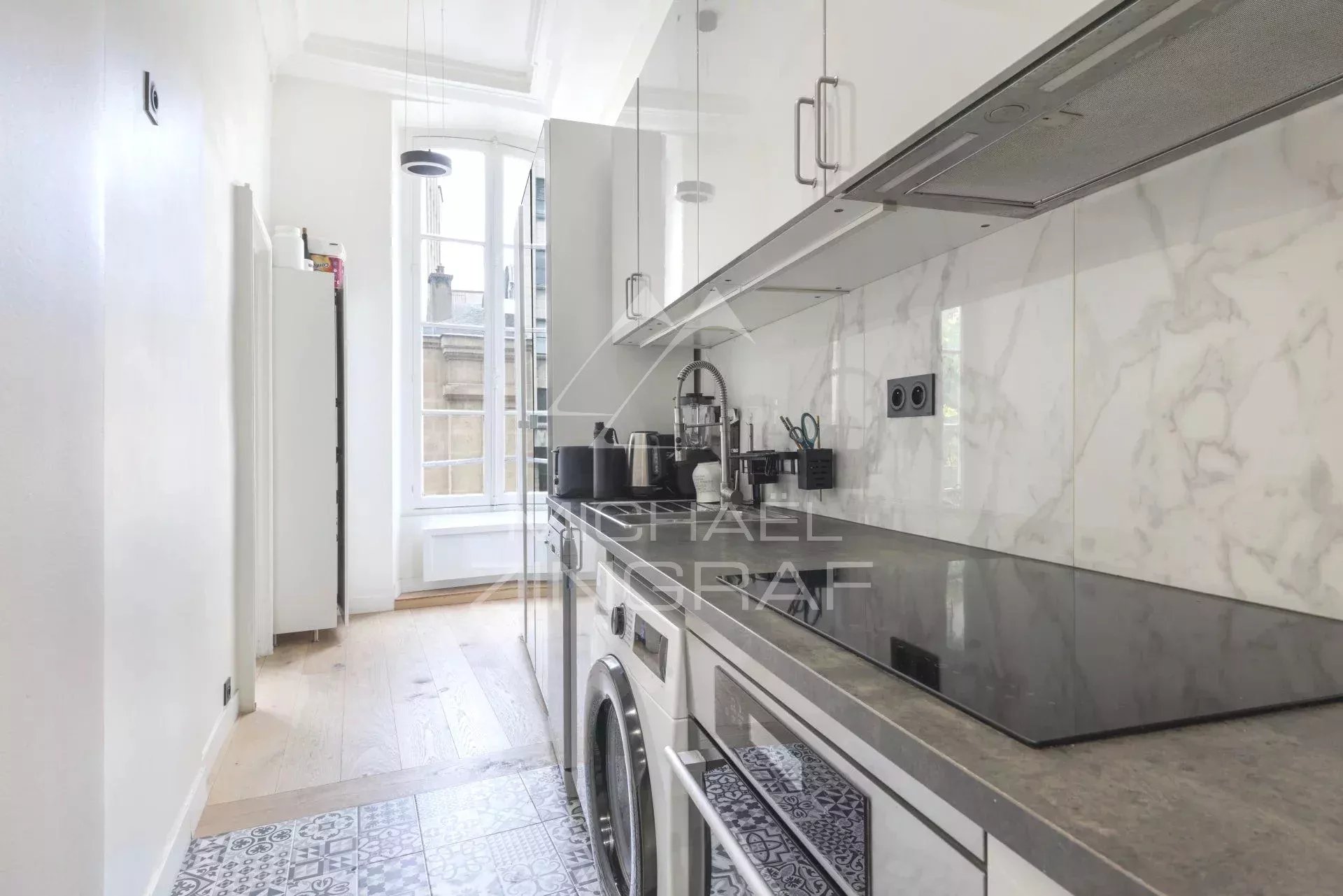 Cuisine d’un appartement à vendre à Paris Cuisine moderne d'un appartement à Paris, avec des appareils électroménagers et un sol en carrelage.