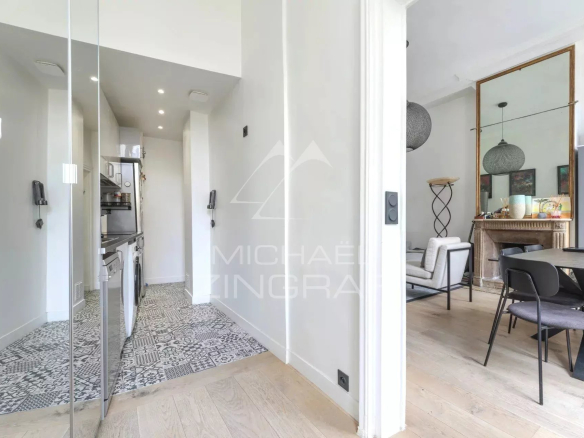 Intérieur d'un appartement rénové à Paris, montrant une cuisine et un salon lumineux.