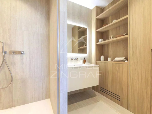 Salle de bain moderne avec douche et meuble en bois clair.