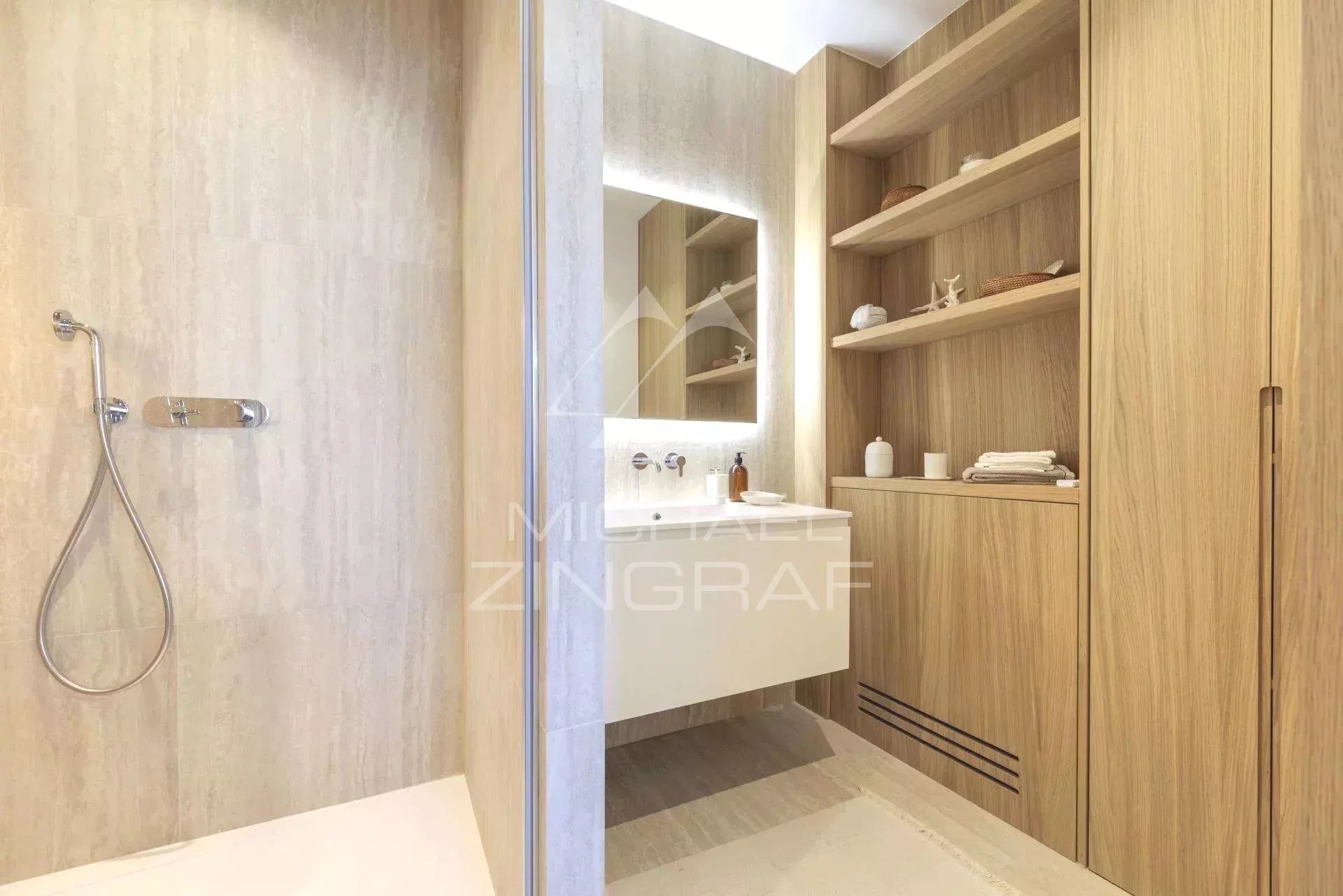 Salle de bain moderne avec douche et meuble en bois clair.