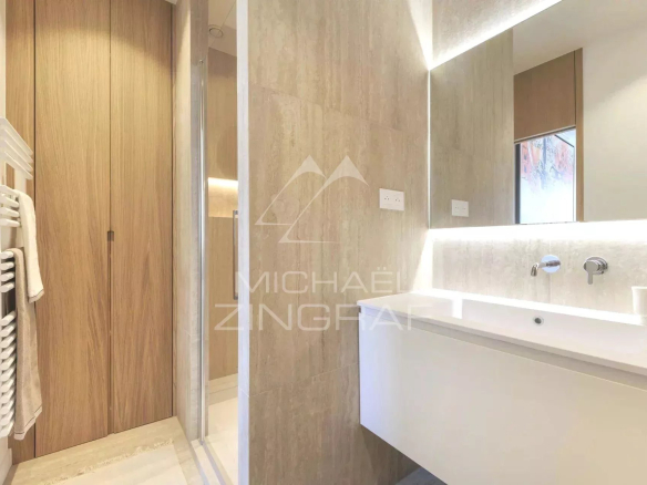 Salle de bain moderne avec douche et lavabo dans un appartement rénové à Paris.
