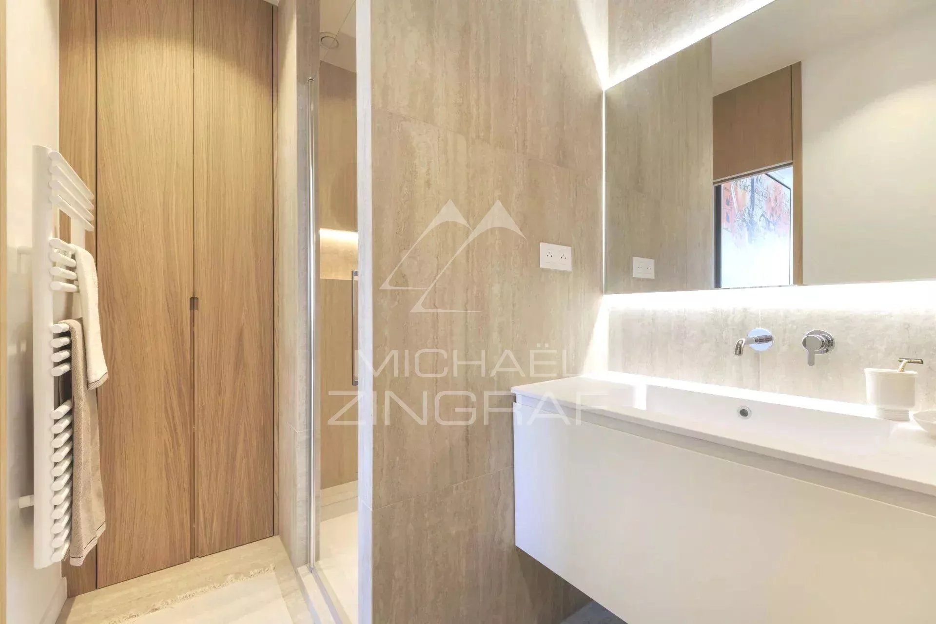 Salle de bain moderne avec douche et lavabo dans un appartement rénové à Paris.