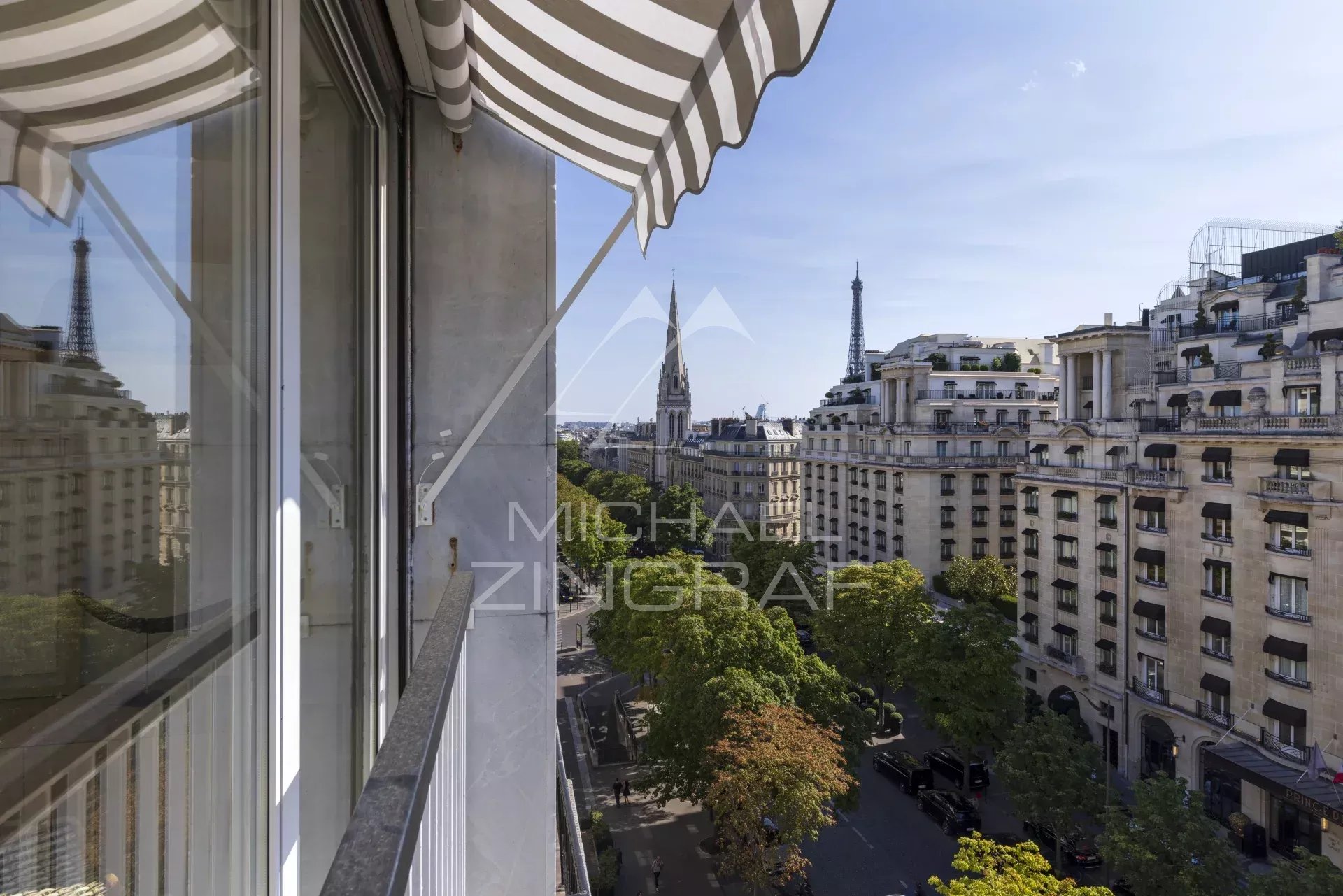 Vue depuis un appartement au 7ème étage sur l'Avenue George V à Paris, avec des bâtiments haussmanniens et la tour Eiffel en arrière-plan.