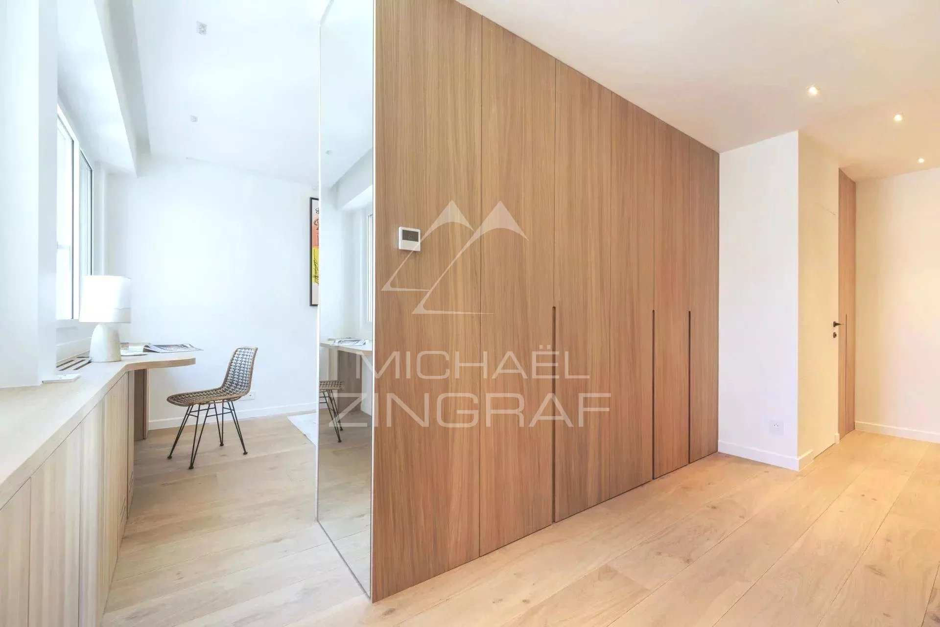Intérieur d'un appartement rénové avec mobilier moderne, parquet clair et murs blancs.