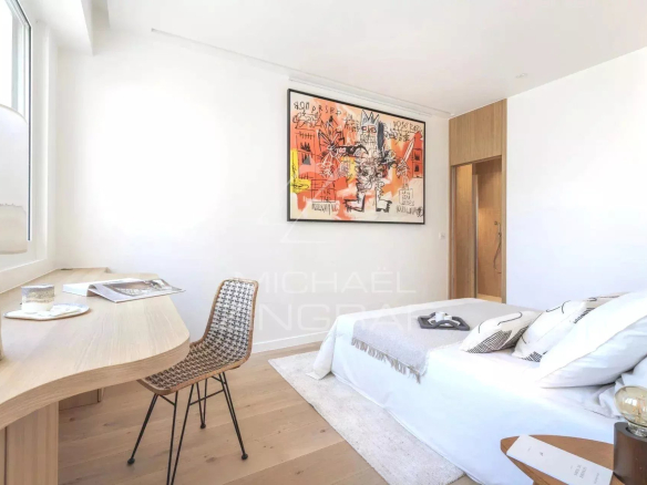 Chambre d'un appartement rénové à Paris, avec un lit, un bureau et une œuvre d'art au mur.