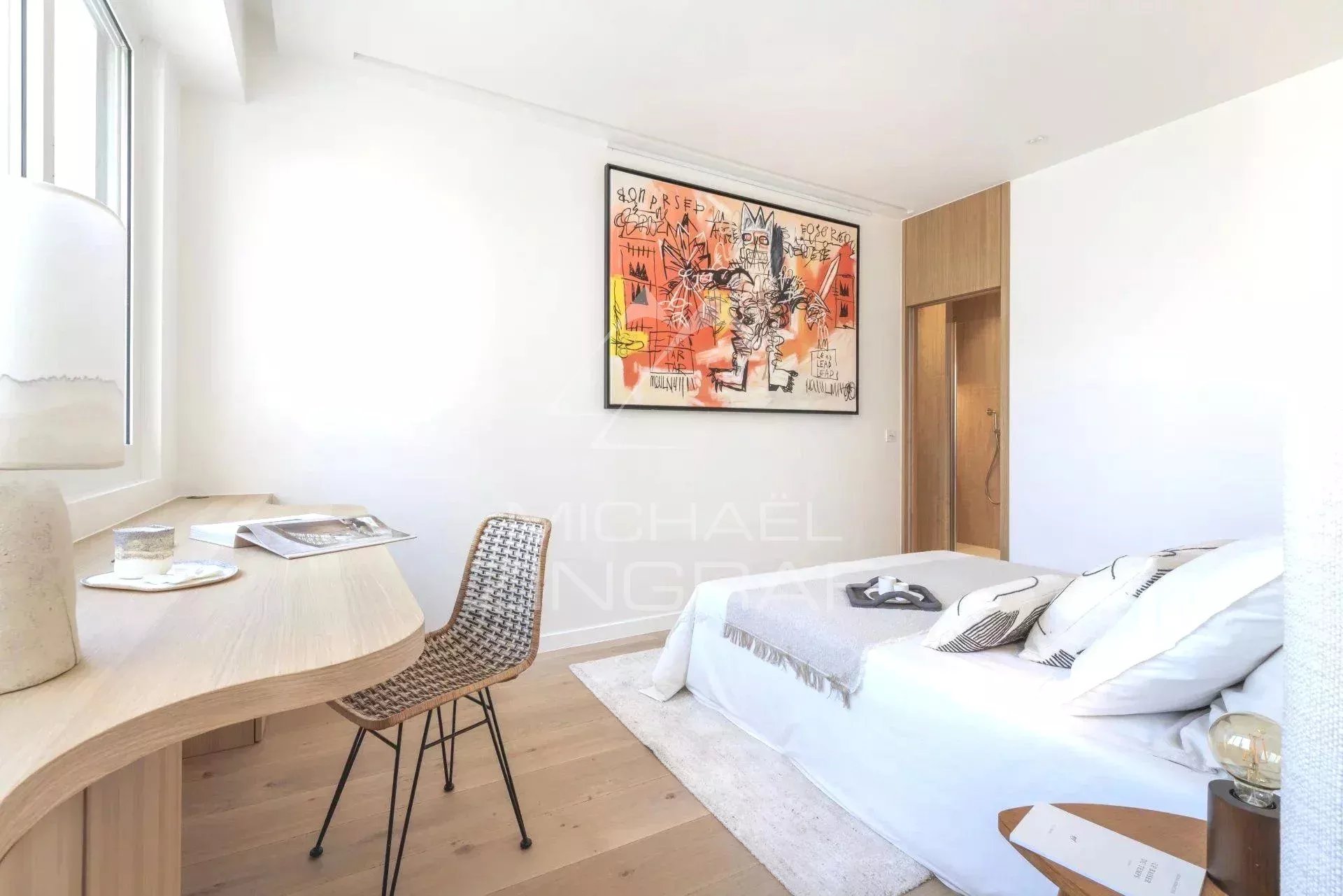 Chambre d'un appartement rénové à Paris, avec un lit, un bureau et une œuvre d'art au mur.