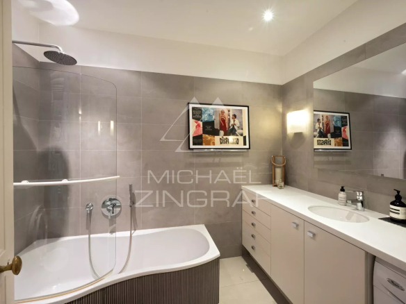 Salle de bain moderne avec baignoire et douche, miroir et meubles de rangement.