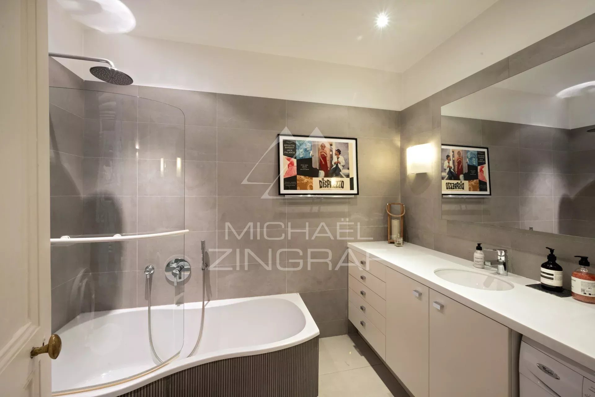 Salle de bain moderne avec baignoire et douche, miroir et meubles de rangement.