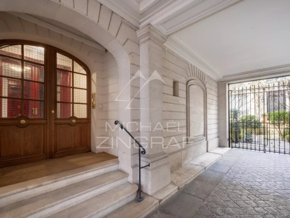 Entrée d'un immeuble avec porte en bois et cour intérieure à Paris 7ème.