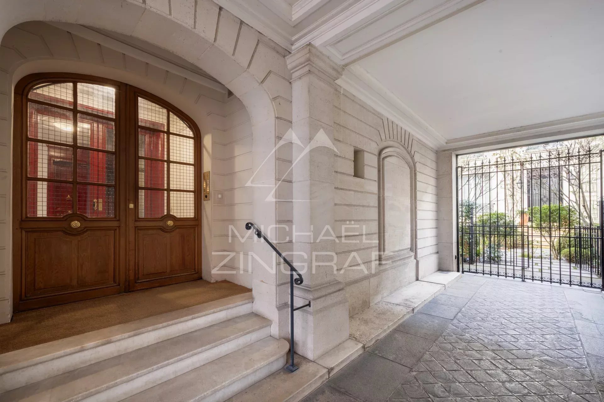 Entrée d'un immeuble avec porte en bois et cour intérieure à Paris 7ème.