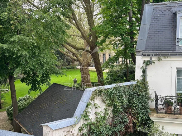 Vue sur un jardin depuis un appartement à Paris 7ème, entouré d'arbres et de verdure.