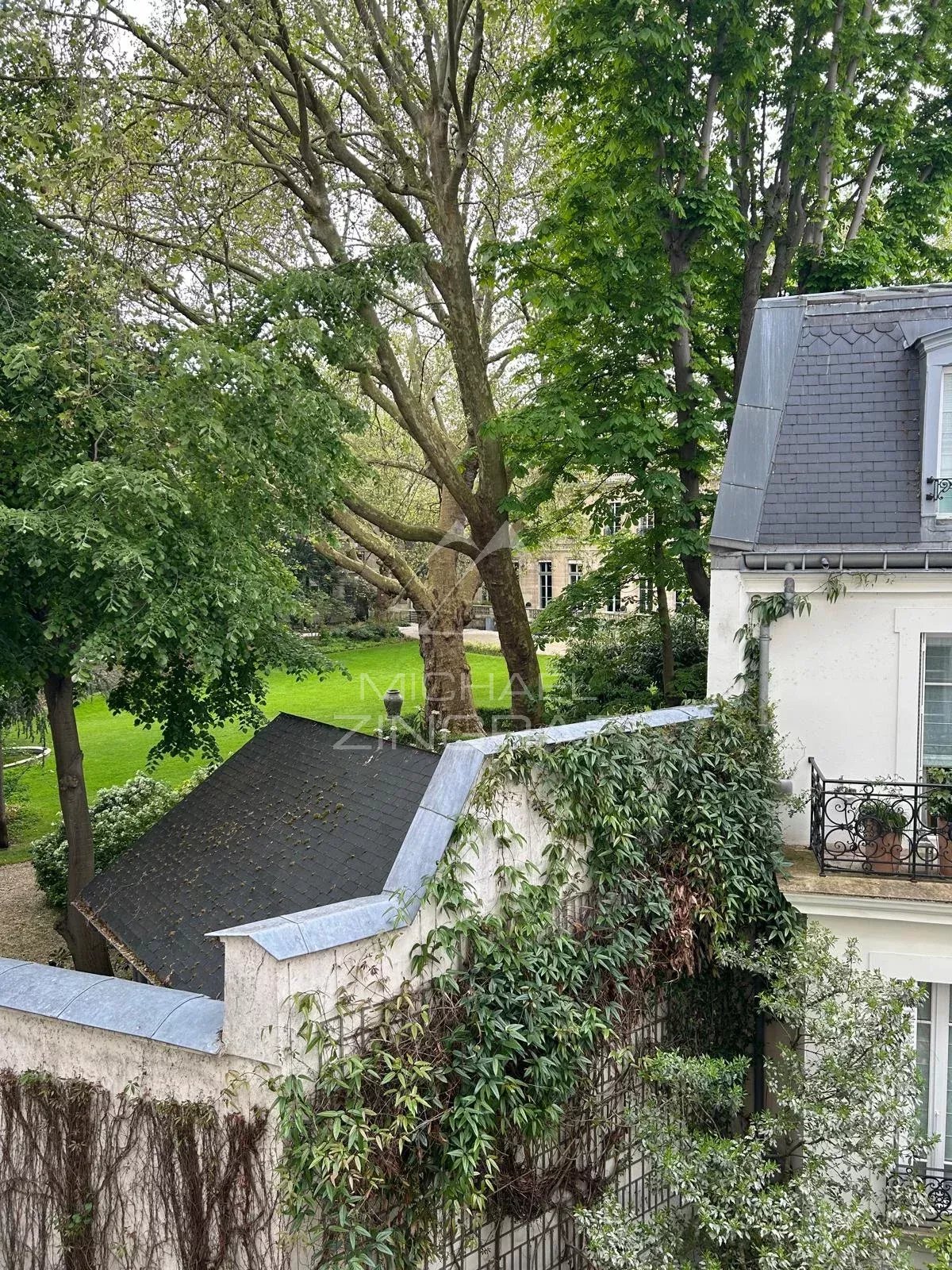 Vue sur un jardin depuis un appartement à Paris 7ème, entouré d'arbres et de verdure.