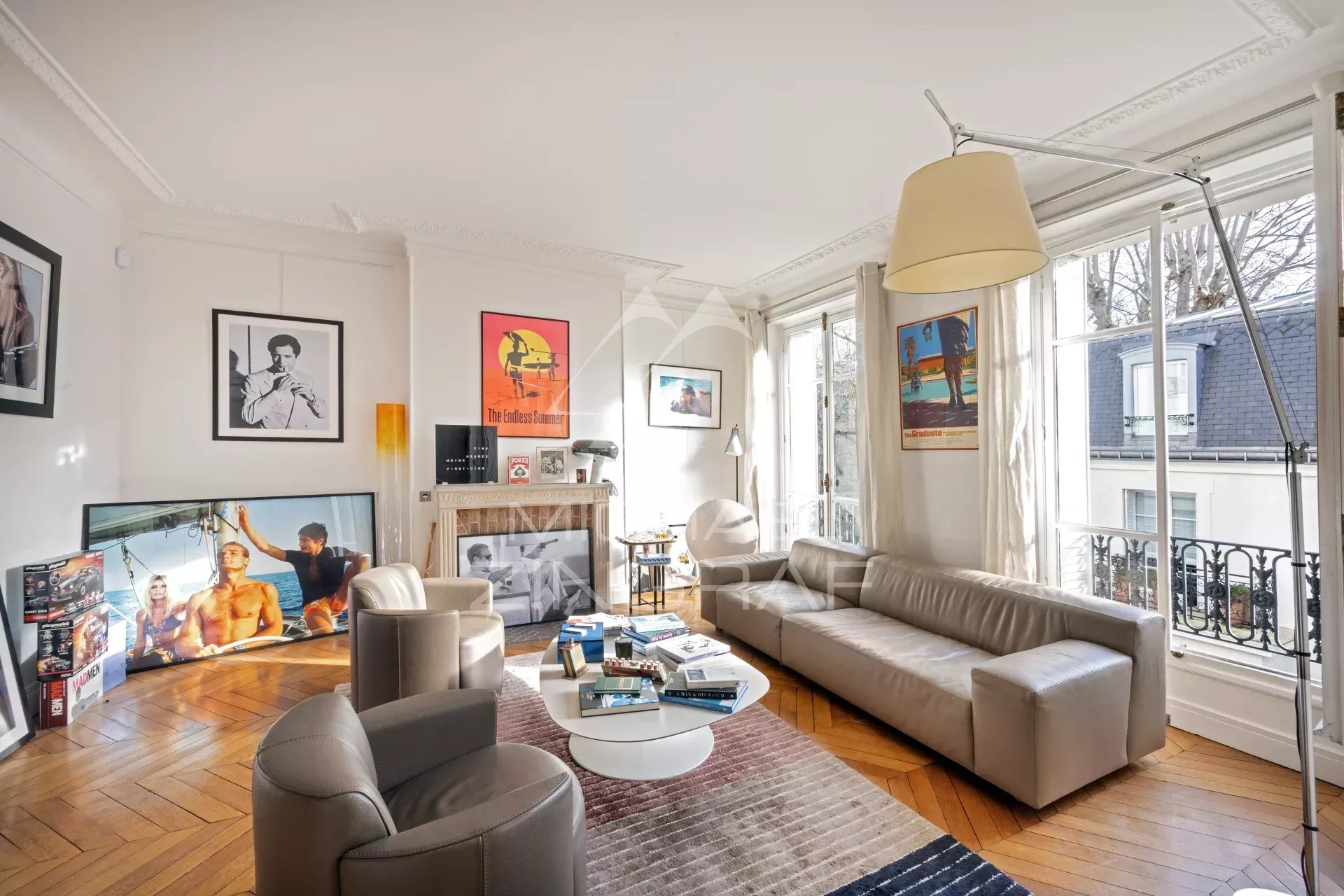 Salon lumineux d'un appartement de 115 m2 à Paris, avec canapé, cheminée et œuvres d'art aux murs.