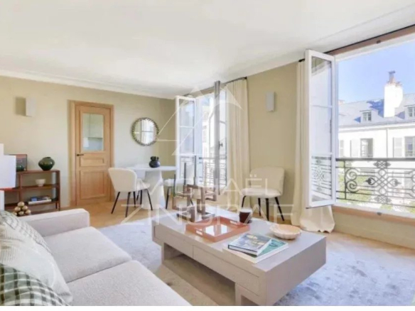 Bright living room of a furnished apartment in Paris with open windows and garden views.