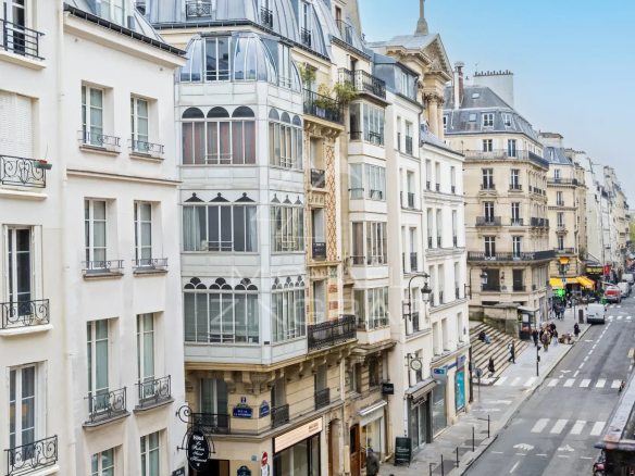 Vue de la rue Saint Honoré à Paris, montrant des bâtiments et des commerces.
