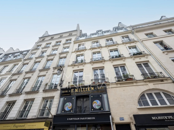 Façade d'un immeuble sur la rue Saint-Honoré à Paris, avec commerces en bas.