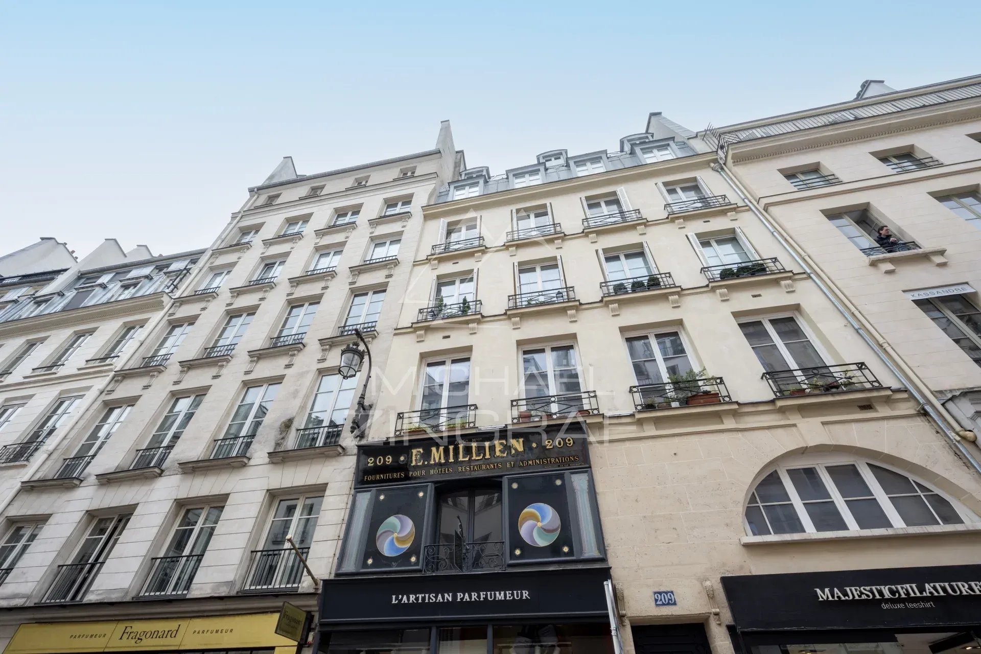 Façade d'un immeuble sur la rue Saint-Honoré à Paris, avec commerces en bas.