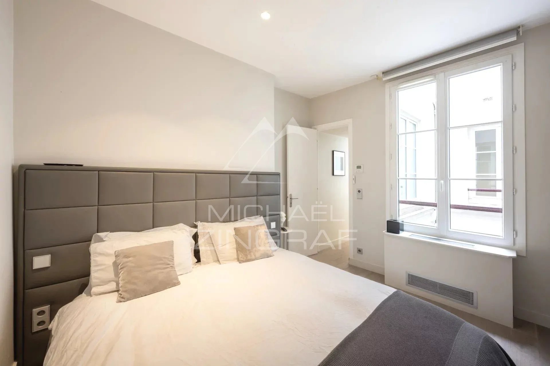 Chambre d'un appartement à Paris, avec un lit et une fenêtre laissant entrer la lumière.