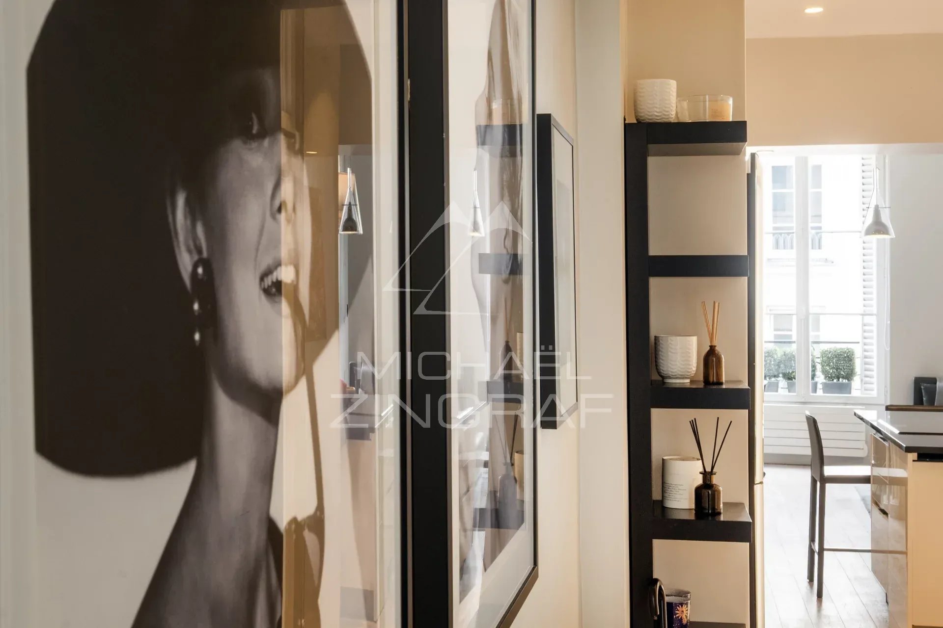 Intérieur d'un appartement avec un portrait en noir et blanc et des étagères décoratives.