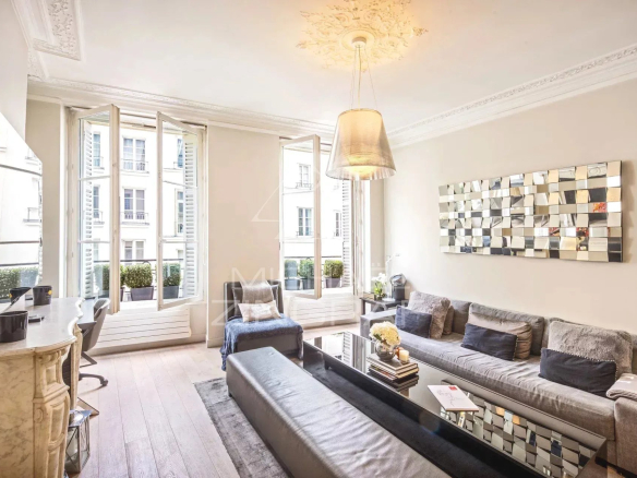 Salon lumineux avec canapé et table basse, fenêtres ouvertes sur cour, décor moderne.