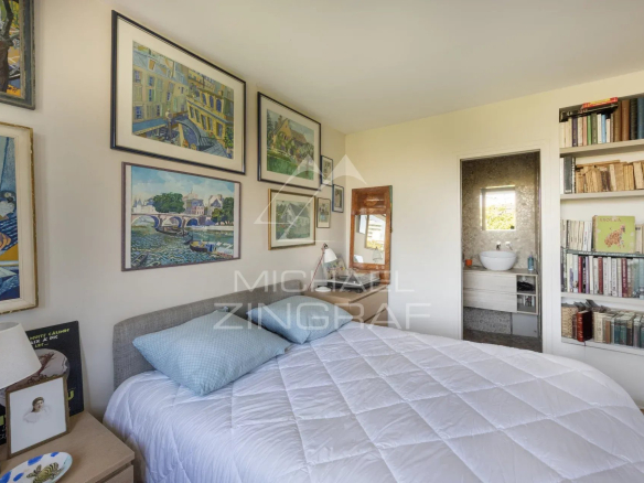 Chambre d'un penthouse à Paris avec lit, bibliothèque et œuvres d'art au mur.