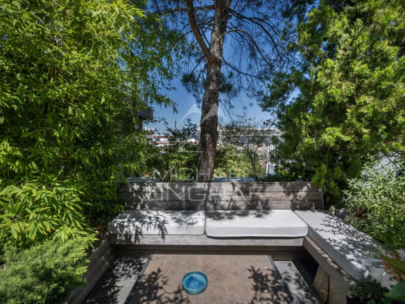 Espace extérieur d'un penthouse avec jardin, bancs et vue sur la ville.