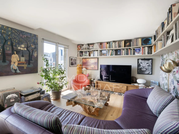 Salon d'un penthouse à Paris 15, avec canapé, bibliothèque et œuvres d'art.