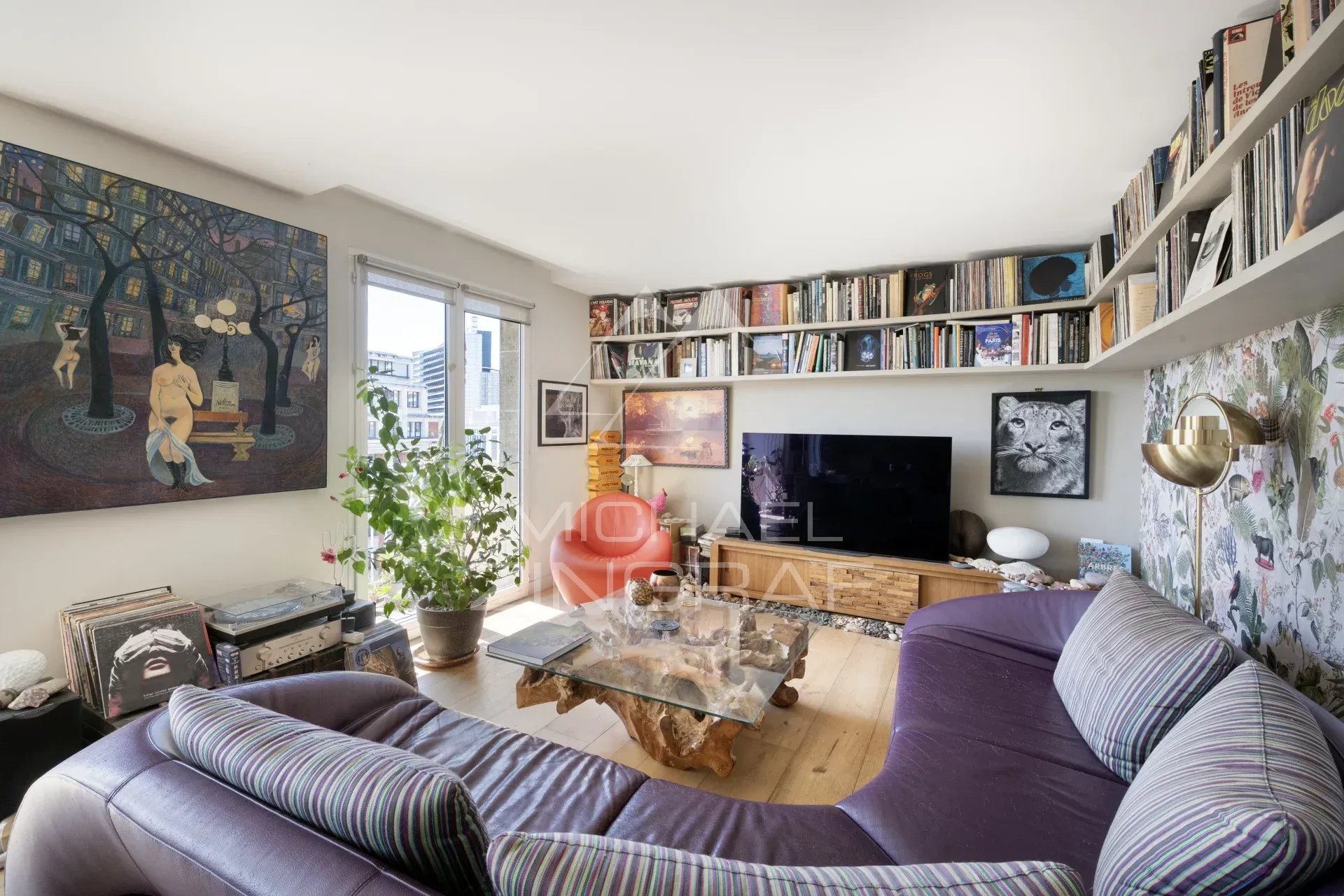 Salon d'un penthouse à Paris 15, avec canapé, bibliothèque et œuvres d'art.