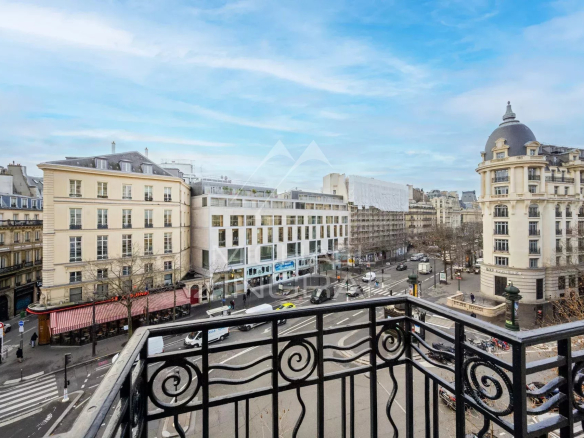 Vue depuis un balcon d'un appartement à Paris, montrant des bâtiments et une rue animée.