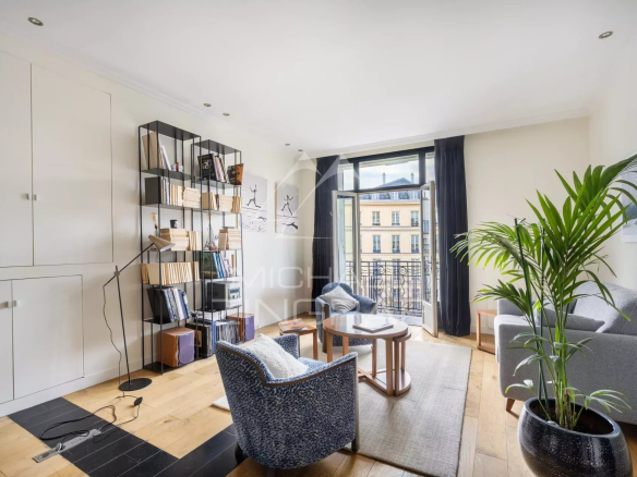 Intérieur d'un appartement à Paris avec un salon lumineux et un balcon.