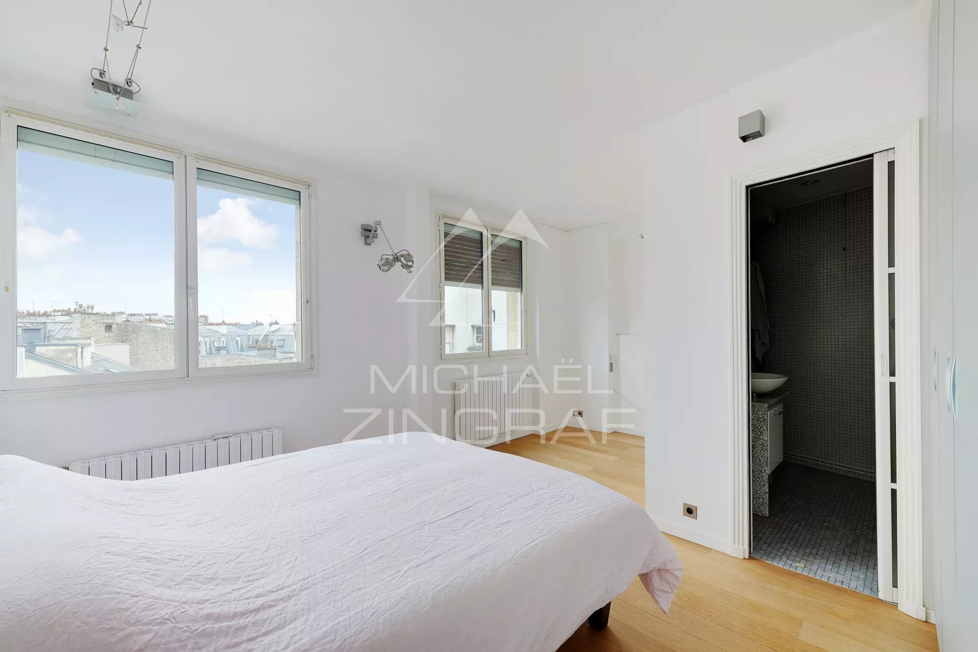 Chambre d’appartement à vendre à Paris 6ème Chambre d'appartement moderne avec vue sur Paris, fenêtre et salle de bain attenante.
