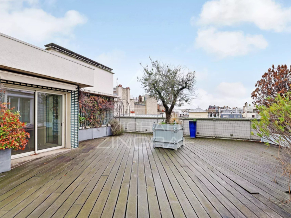 Spacious terrace of a top-floor apartment in Paris, with views over the rooftops.