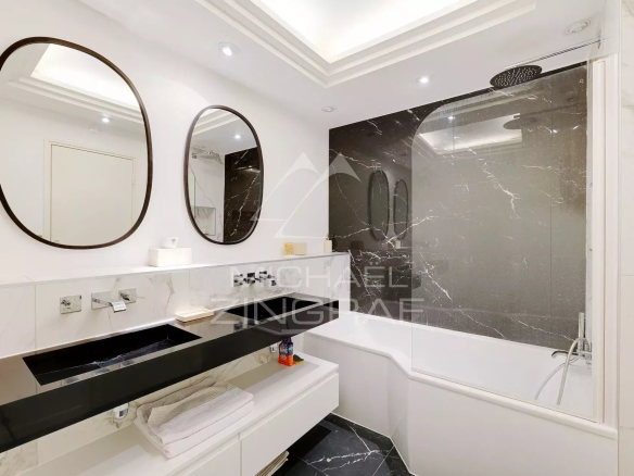 Salle de bain moderne avec baignoire et lavabo, murs en marbre noir et blanc.