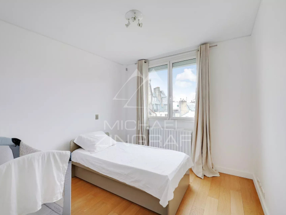 Chambre d'un appartement moderne à Paris, avec un lit simple et une fenêtre.