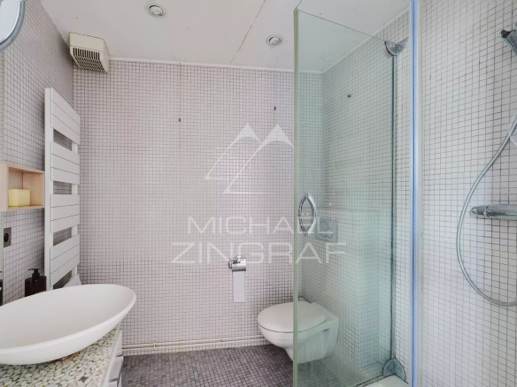 Salle de bain moderne avec douche en verre et lavabo dans un appartement à Paris.
