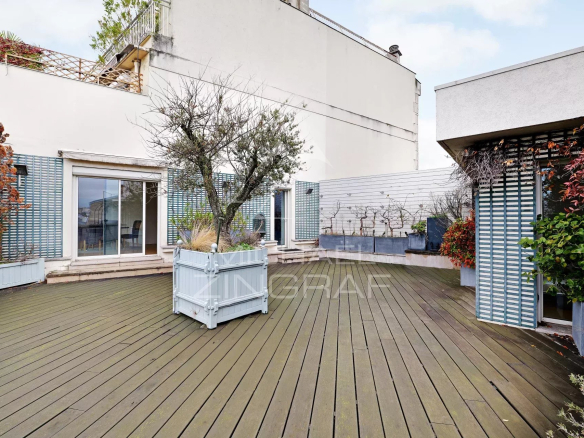 Terrasse spacieuse d'un appartement au dernier étage à Paris, avec plantes et mobilier extérieur.