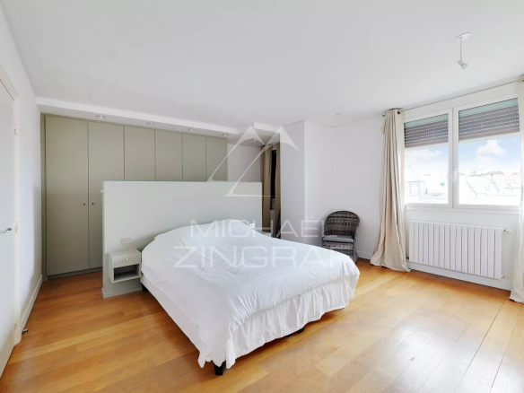 Chambre d'un appartement à vendre à Paris, avec un lit et des placards intégrés.