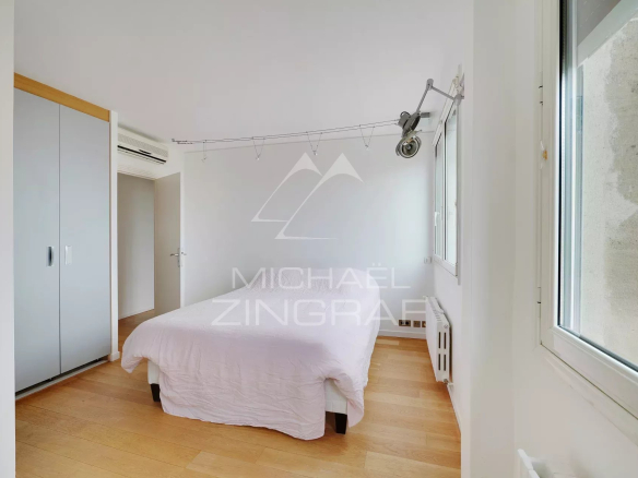 Chambre d'un appartement à vendre à Paris 6ème, avec un lit et des placards.