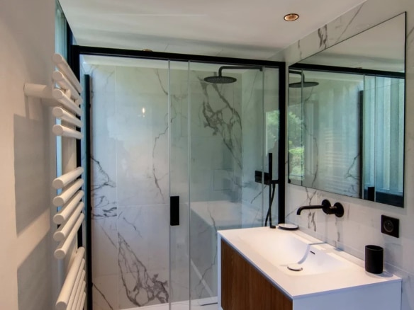 Modern bathroom with glass shower and wooden vanity unit.