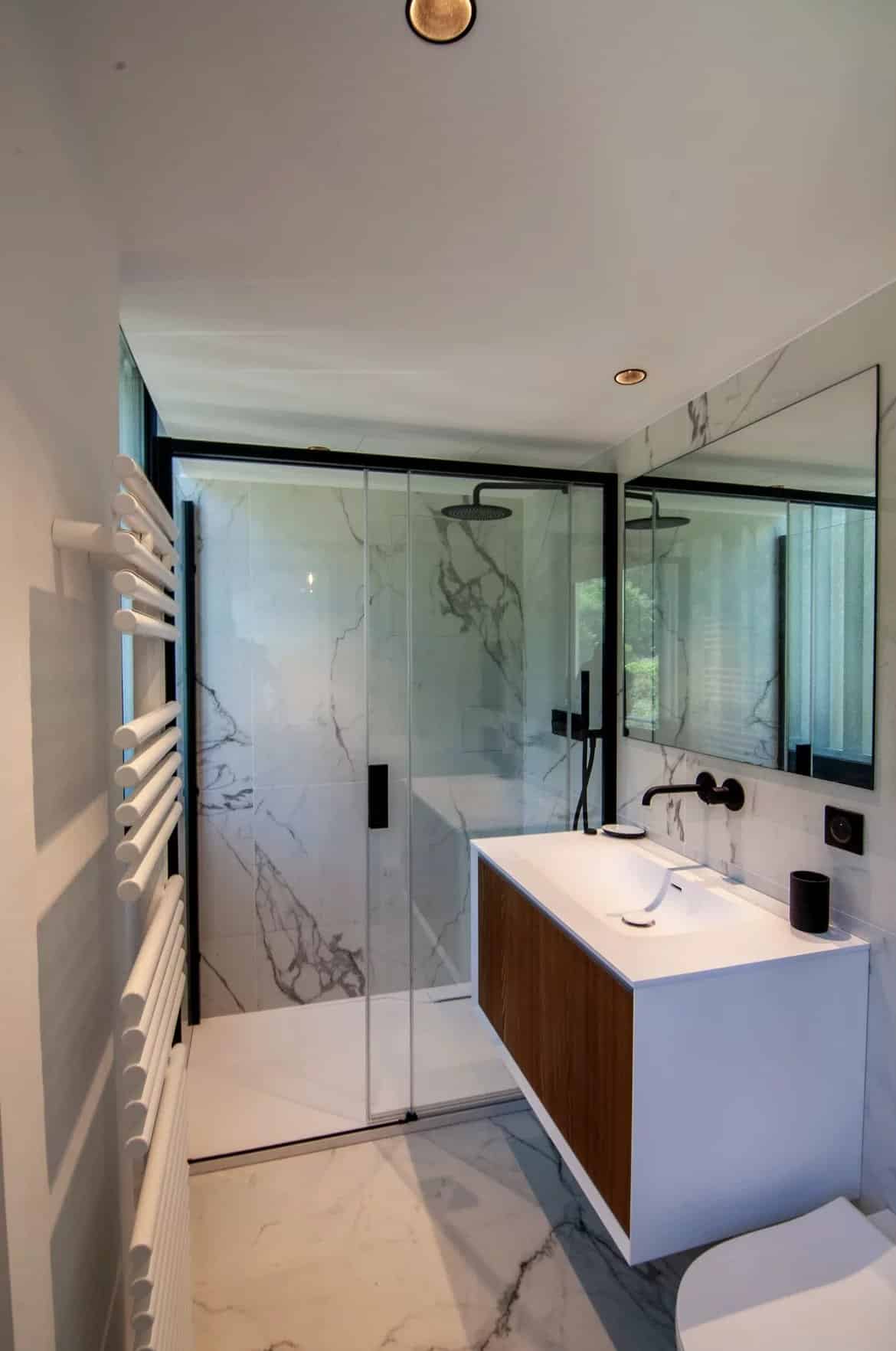 Modern bathroom with glass shower and wooden vanity unit.