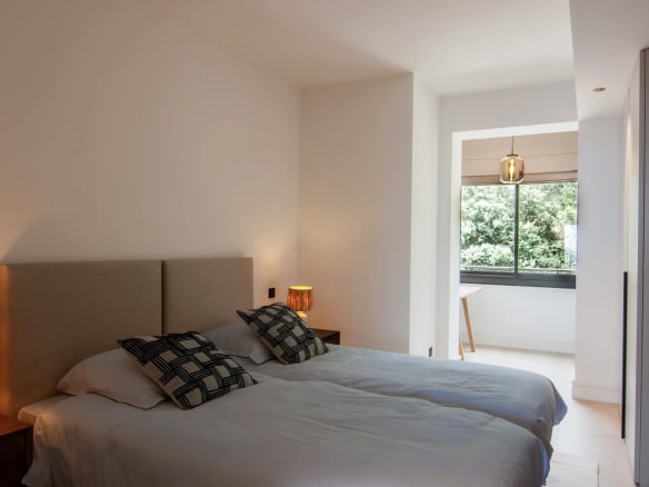Double room with twin beds and windows overlooking a green outdoor space.