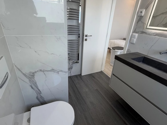 Salle de bain moderne avec carrelage marbré et meubles contemporains.