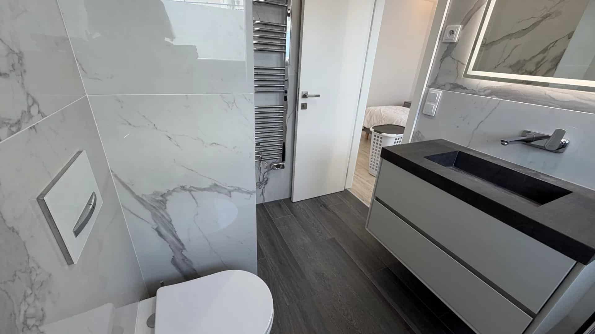 Salle de bain moderne avec carrelage marbré et meubles contemporains.