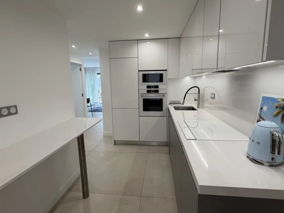 Cuisine moderne et lumineuse d'un appartement à Cannes, avec plans de travail en blanc et appareils intégrés.