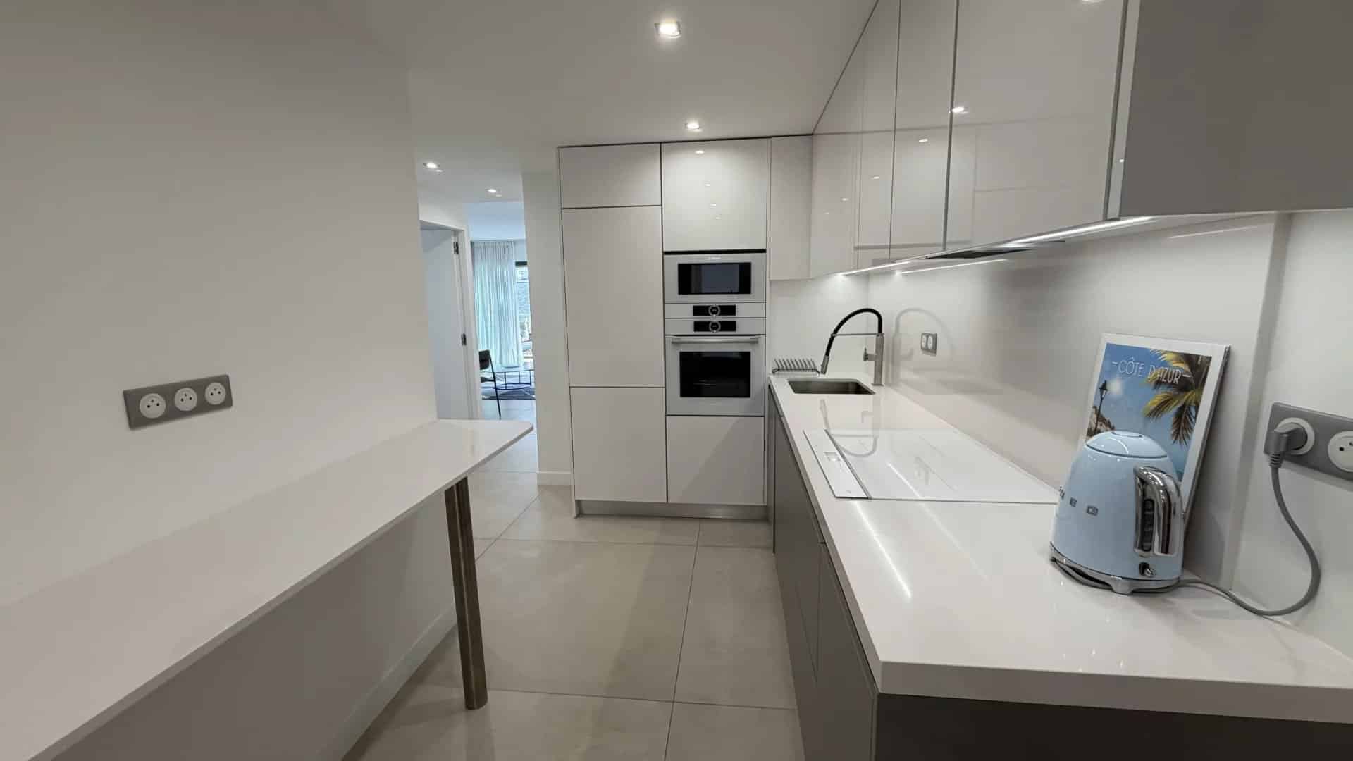 Cuisine moderne et lumineuse d'un appartement à Cannes, avec plans de travail en blanc et appareils intégrés.